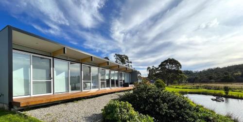 a modern house with glass windows and a river at Pelican Point Tasmania in St Helens