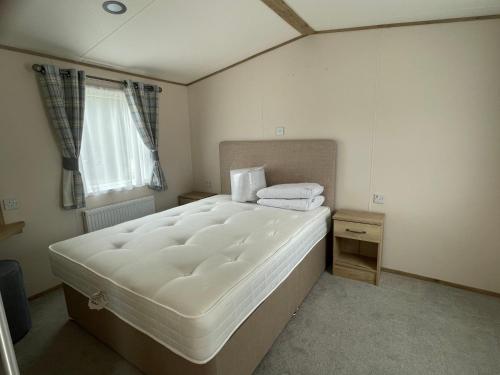 1 dormitorio con 1 cama blanca grande y ventana en Emma's Pad at Hoburne Naish - New Forest - Wheel chair Accessible with wetroom and ramp en Highcliffe