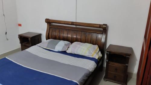 1 cama con cabecero de madera y 2 mesitas de noche en Aparta estudio - paris, en Ciénaga