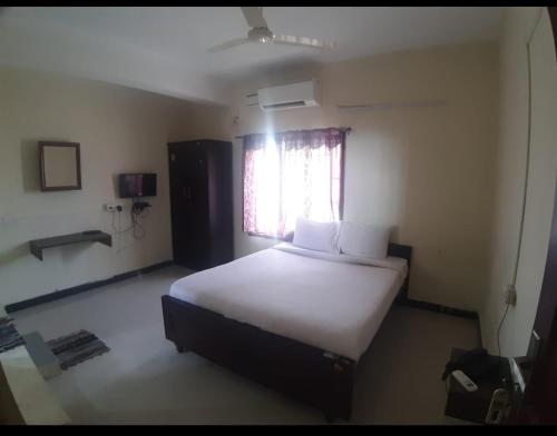 a bedroom with a large white bed with a window at Shree SaiRenu near maruthamalai and bharathiyar univ and on the way to Adiyogi Isha Yoga centre in Marudhamalai