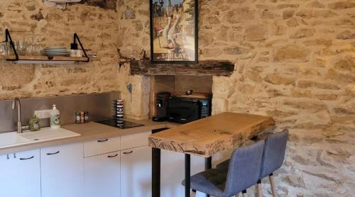 cocina con mesa de madera y pared de piedra en La cachette sarladaise, en Sarlat-la-Canéda