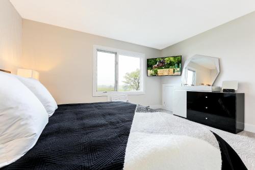 ein weißes Schlafzimmer mit einem großen Bett und einem Spiegel in der Unterkunft Exquisite One of a kind 3BDR Condo at Hilltop 5736 in Traverse City