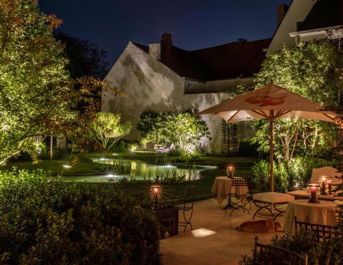 een patio met een parasol en een vijver in de nacht bij The Notary in Brugge