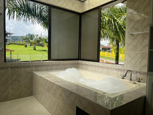 baño con bañera y ventana grande en Hotel Casa Confort en Santa Rosa de Cabal