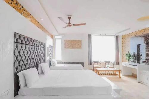 een witte slaapkamer met een groot bed en een plafondventilator bij Super OYO Hotel Vivaan Residency in Rohtak