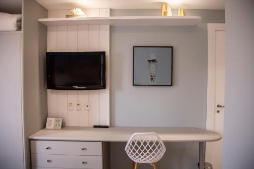a room with a desk and a tv on a wall at Jurerê Beach Village - Studio Vista Mar in Florianópolis