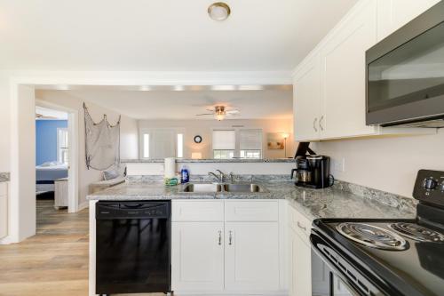 a kitchen with white cabinets and a sink and a stove at Coastal Emerald Isle Retreat with Deck and Grill! in Emerald Isle