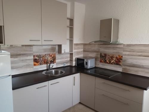 a kitchen with white cabinets and a sink and a microwave at Apartments with a parking space Njivice, Krk - 14932 in Njivice