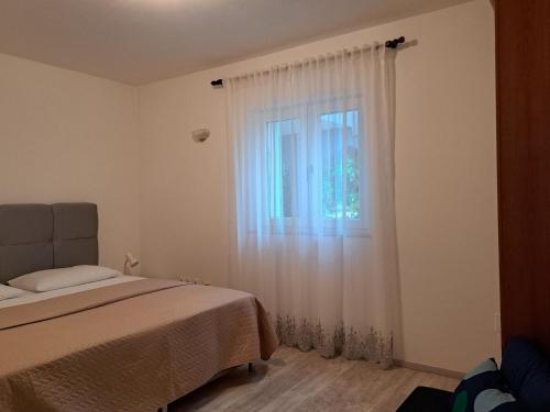 a bedroom with a bed and a window with white curtains at Apartments with a parking space Njivice, Krk - 14932 in Njivice