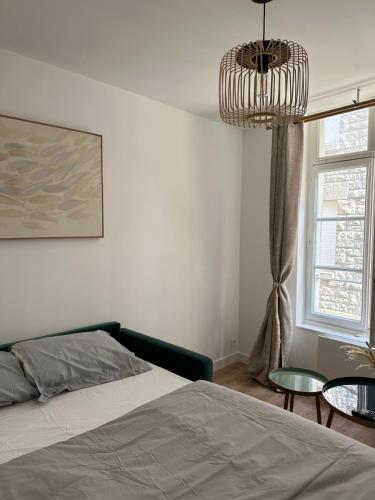 une chambre avec un lit et un lustre dans l'établissement Appartement St-Malo Intramuros, à Saint-Malo