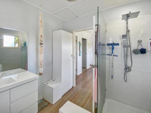 a white bathroom with a shower and a sink at The Shack in Sarina