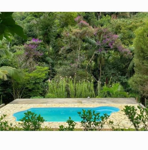 a swimming pool in the middle of a garden at Casa com churrasqueira piscina privativa em São Pedro da Serra - Perto de Lumiar in Nova Friburgo