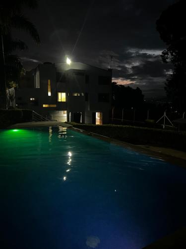 an empty swimming pool at night with a house in the background at Hotel Casa Confort in Santa Rosa de Cabal