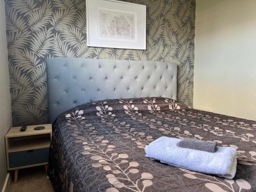 a bedroom with a bed with a blue head board at ASURE Surrey Court Motel Invercargill in Invercargill