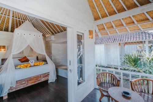 a bedroom with a bed and a table and chairs at Paluh Beach Huts in Nusa Lembongan