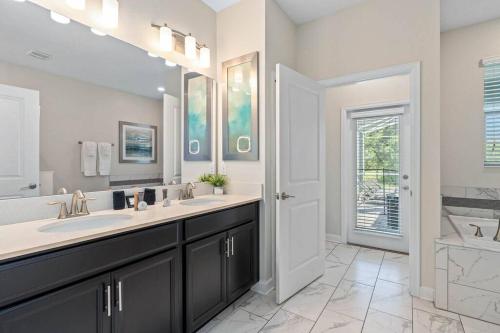 a bathroom with two sinks and a large mirror at Disney 8BR South Pool Theater Arcade Harry Potter Room in Davenport