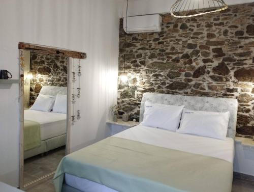 a bedroom with two beds and a stone wall at Karystos Chora Suites in Karistos