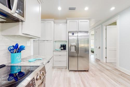 a kitchen with white cabinets and a stainless steel refrigerator at Peace & Sea-Renity in Dauphin Island