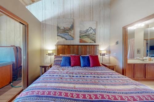 1 dormitorio con 1 cama grande con almohadas azules y rojas en The Mountainside - Unit B47 en Granby