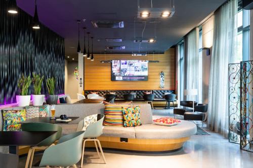 a lobby with a couch and tables and chairs at Moxy Frankfurt Airport in Frankfurt/Main