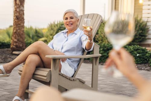 an older woman sitting in a chair holding a glass of wine at Golf Course Living at Palmilla Beach in Port Aransas
