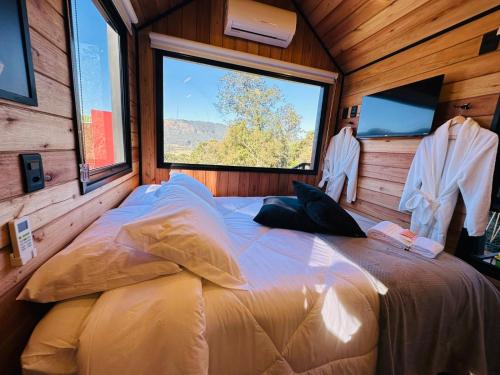 a large bed in a room with a large window at Chalé Harmonia da Floresta- Pousada Cachoeira da Neve in Urubici