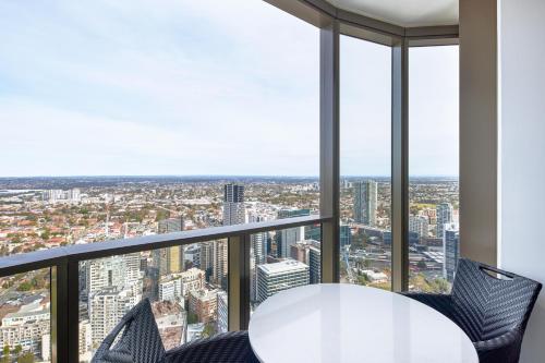 a white table and chairs in a room with windows at Meriton Suites George Street, Parramatta in Sydney