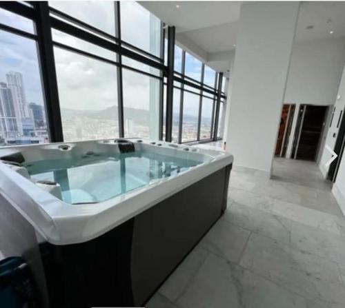 uma grande banheira num quarto com janelas em La comodidad de un hogar na Cidade do Panamá