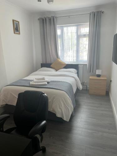 a bedroom with a bed and a chair and a window at Starlet Property in Wanstead