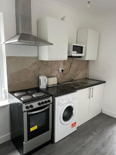 a kitchen with a stove and a washing machine at Starlet Property in Wanstead