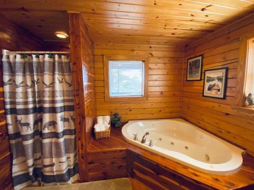 a bathroom with a tub in a log cabin at Chalet with a view at Bear Mountain - Hottub in Eureka Springs