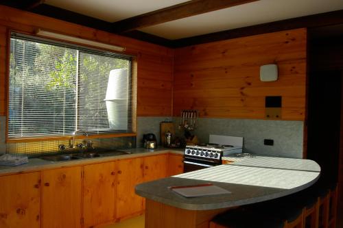 a kitchen with wooden cabinets and a stove and a window at Edge of the Bay Resort in Coles Bay