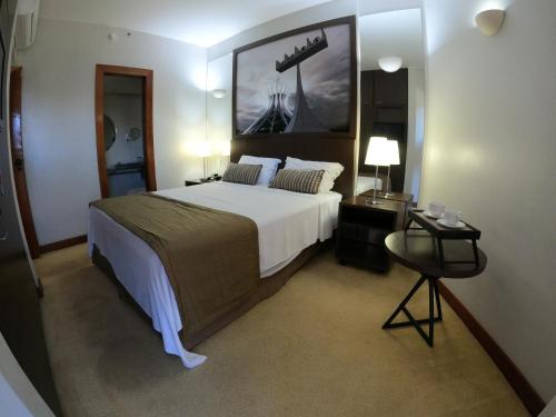 1 dormitorio con 1 cama grande y una pintura en la pared en Bonaparte Hotel - Excelente Apartamento #1402 en Brasilia