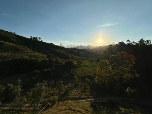 a view of a valley with the sun setting in the background at Recanto João de barro in Visconde De Maua