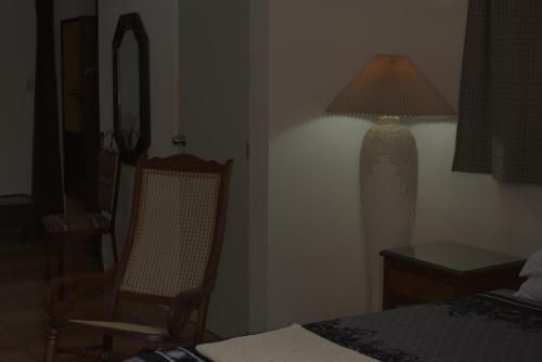 a bedroom with a bed and a chair and a lamp at La Casa del Chac in Mérida