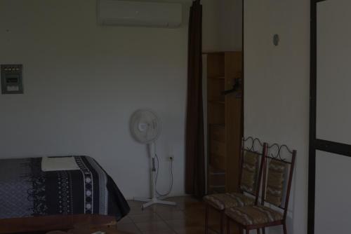 a room with a fan and two chairs in a room at La Casa del Chac in Mérida