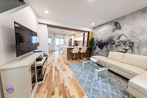 a living room with a white couch and a tv at Le Petit Manoir - Quartz in Lac-Simon