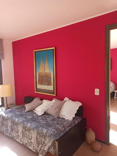 a bedroom with a red wall with a bed at Lara in Mendoza