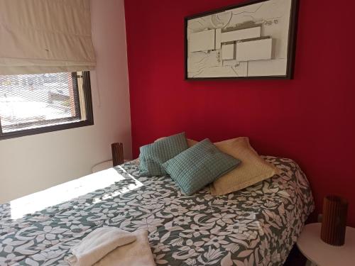 a bedroom with a bed with a red wall at Lara in Mendoza