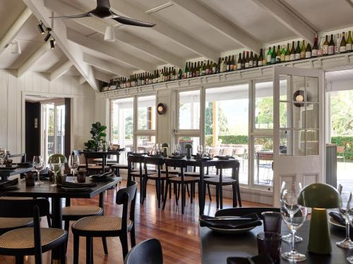 a dining room with tables and chairs and windows at The Lodge Bellingen in Bellingen