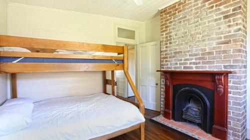 a bedroom with a bunk bed and a brick fireplace at Reflections Yamba Lighthouse Cottages in Yamba