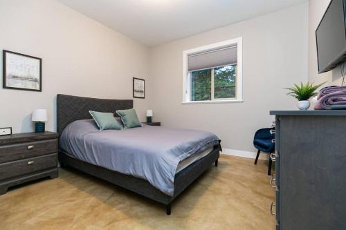 a bedroom with a bed and a dresser and a television at Water Front Home with Private Dock and Hottub in Sooke