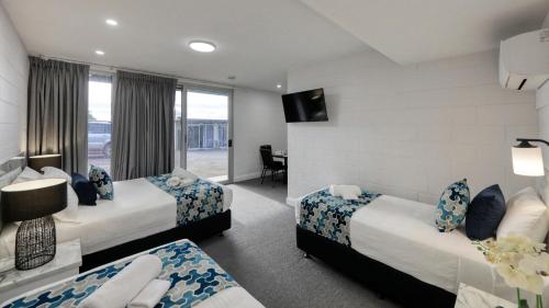 a hotel room with two beds and a television at Hilltop Motel in Broken Hill