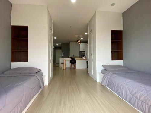 a bedroom with two beds and a kitchen in it at A Modern & Homely Studio with Pool and Gym in Kampar