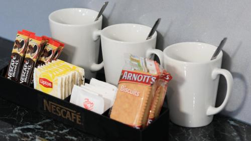 three coffee mugs and some snacks on a table at Hilltop Motel in Broken Hill
