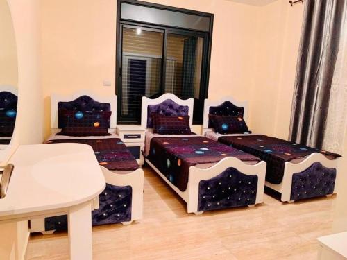 傑里科的住宿－villa wardet algabal，带三张床和一张桌子的房间