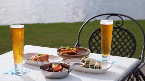 a table with two glasses of beer and plates of food at Grand Pacific Hotel in Suva