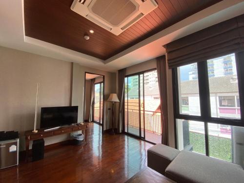 a living room with a couch and a tv and windows at Yotaka Bangkok Hotel in Bangkok
