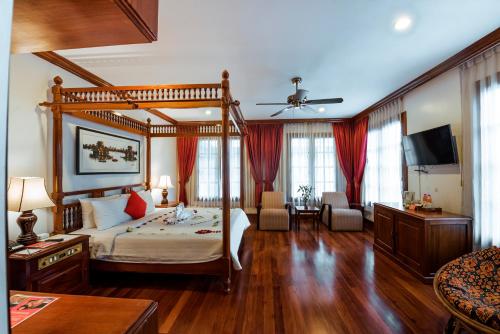 1 dormitorio con cama con dosel y sala de estar. en Royal Crown Hotel Siem Reap, en Siem Reap