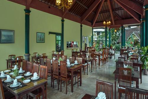 une salle à manger avec des tables et des chaises en bois dans un restaurant dans l'établissement Margo Utomo Eco Resort, à Banyuwangi
